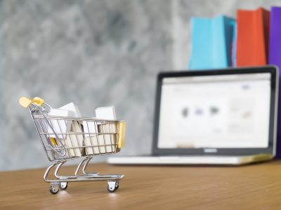 Business theme, internet online shopping concept, shopping delivery, shopping cart carry shopping mail box and blur background of shopping bag and open laptop