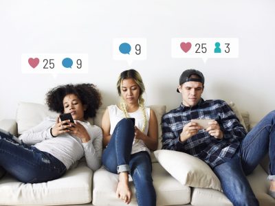 Young adults on the couch using social media on their smartphones